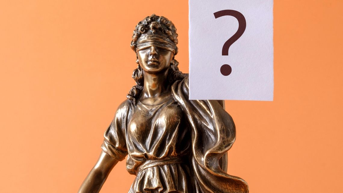 statue av rettferdighet som holder et spørsmålstegn