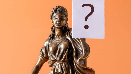 Statue av rettferdighet som holder et spørsmålstegn